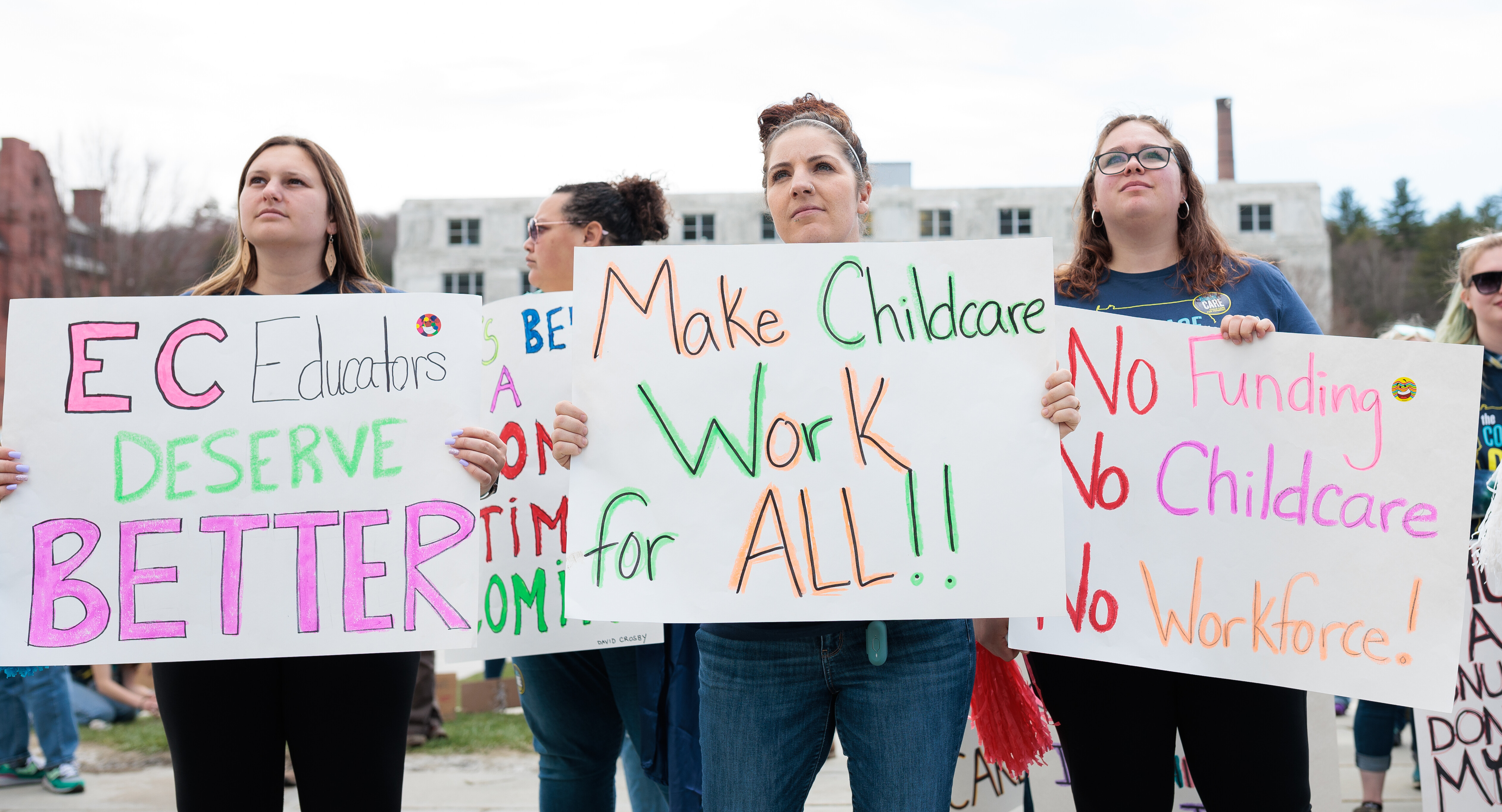 Rally attendees hold signs support a 2023 child care bill.