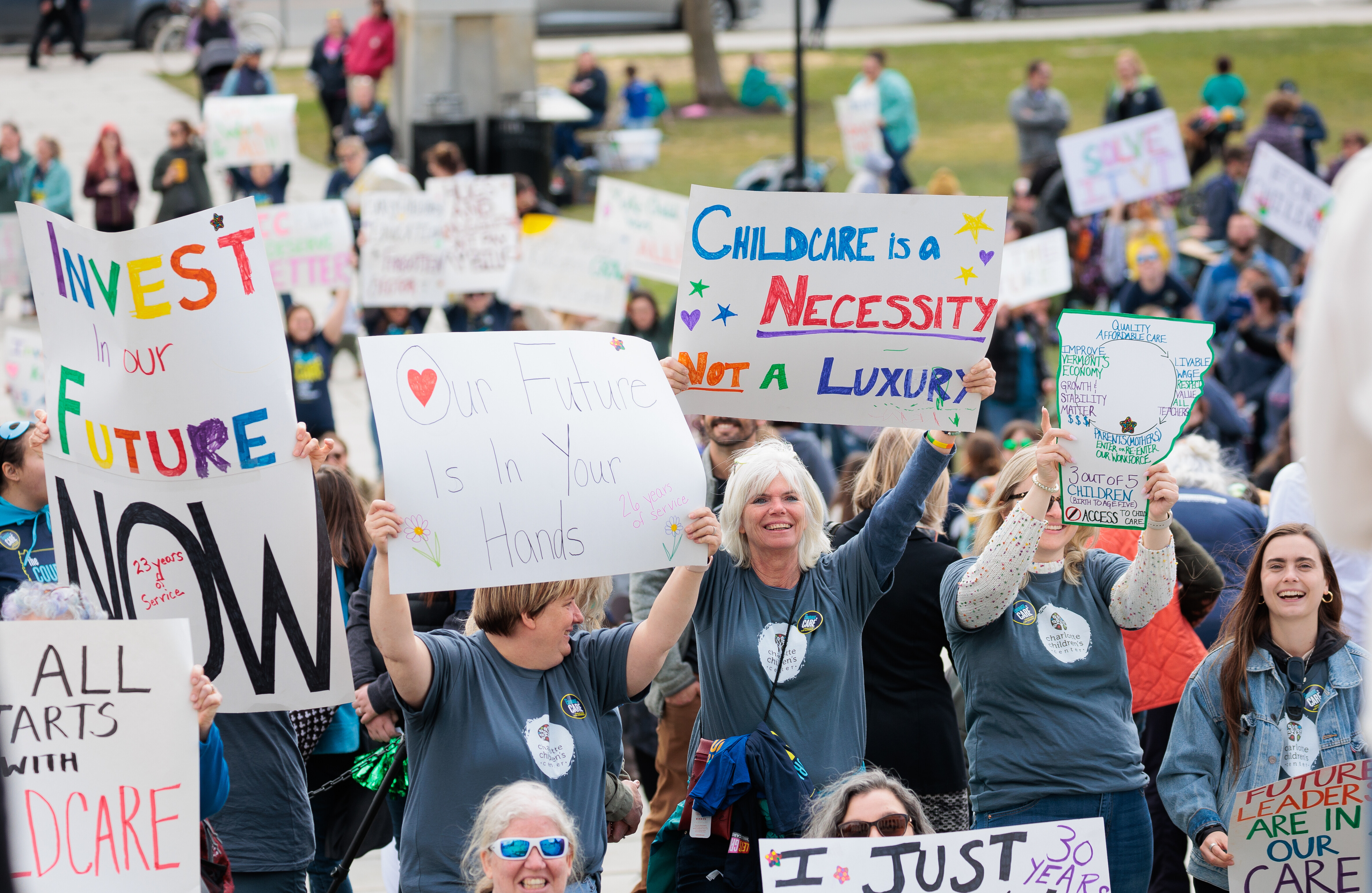 Rally goers hold signs to show support for the 2023 Child Care Bill